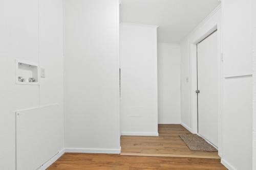 A hallway with a wooden floor and white walls.