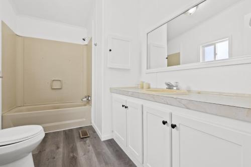 A bathroom with white cabinets and wood floors.