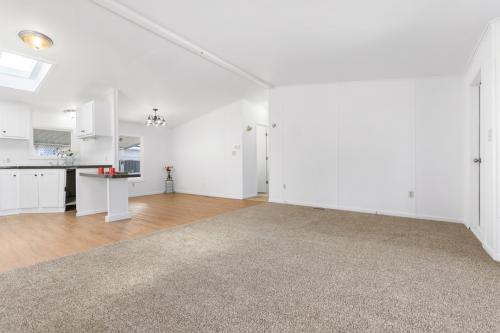 An empty living room with white walls and carpet.