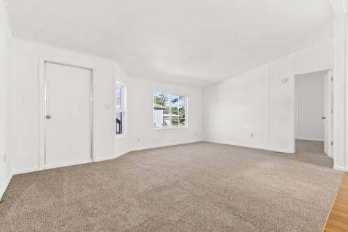 An empty room with white walls and beige carpet.