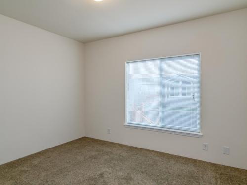 An empty room with a window and carpet.